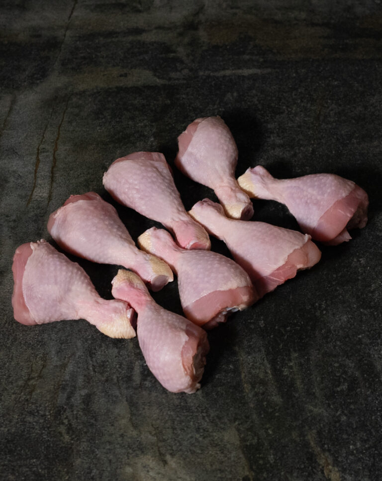 Chicken Drumsticks vom deutschen Hähnchen, auf Schneidebrett mit Kräutern
