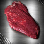 Flanksteak Simmentaler Alpenrind roh – zart marmoriertes Alpenweidefleisch auf gebürstetem Metall, elegant ausgeleuchtet