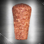 Berliner Döner Kebab Spieß aus handgeschichtetem Hähnchenfleisch, roh und mariniert auf dunkler, edler Unterlage präsentiert.