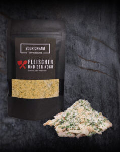 Schüssel mit Sour Cream Onion Dip, umgeben von Kräutern und Zwiebelstücken